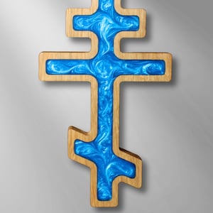 Puede incluir: Cruz ortodoxa de madera con marco marrón claro y centro azul vibrante. El centro azul tiene un patrón arremolinado, creando una textura visual única. Símbolo religioso, adecuado para exhibición.