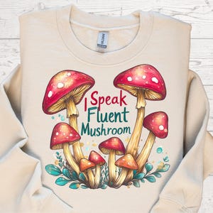 May include: A beige sweatshirt with a graphic of red and white mushrooms and the text "I Speak Fluent Mushroom".