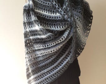 May include: A black and white crocheted shawl with a sparkly thread. The shawl is draped over a mannequin and has a scalloped edge.