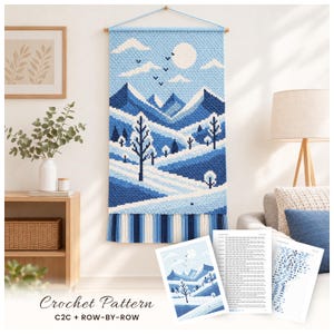 May include: A rectangular crochet wall hanging featuring a blue and white winter mountain landscape with trees, clouds, and a sun. Below the hanging are printed pattern sheets labeled Crochet Pattern C2C + ROW-BY-ROW.