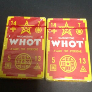 Op de afbeelding: Twee rode en gele speldozen met de tekst "Whot! Een spel voor iedereen" en de nummers 5, 7, 13 en 14 op de voorkant.