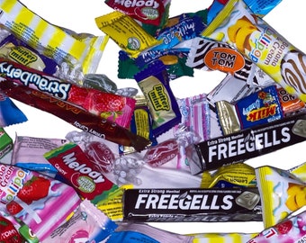 Peut inclure: Assortiment d'emballages de bonbons colorés avec différentes saveurs et marques, notamment Strawberry, Melody, Butter Mint, Tom Tom, Freegells et Maxi Fruity. Les emballages sont disposés en pile sur un fond blanc.
