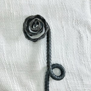 May include: A black metal rose with a stem that is twisted into a spiral shape. The rose is made from a single piece of metal and is a unique and decorative piece.