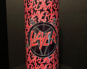 May include: A stainless steel tumbler with a repeating red and white "SLAYER" text pattern on a black background. The center features a black pentagram with the word "SLAYER" in red. The tumbler is cylindrical and designed for beverages.