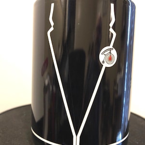 May include: Black ceramic mug with a white design of a suit jacket and a small bicycle with a red wheel.