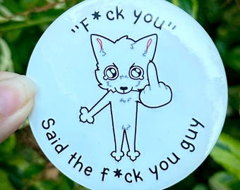 May include: A circular white sticker featuring a black-outlined cartoon fox with large eyes. The fox is holding up its middle finger. The text "F*ck you" is printed above the fox, and "Said the f*ck you guy" is printed below the fox.