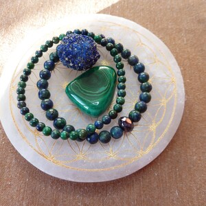 Peut inclure: Deux bracelets en perles bleues et vertes avec une pierre de malachite verte et une pierre d'azurite bleue sur une plaque de rechargement en sélénite blanche.