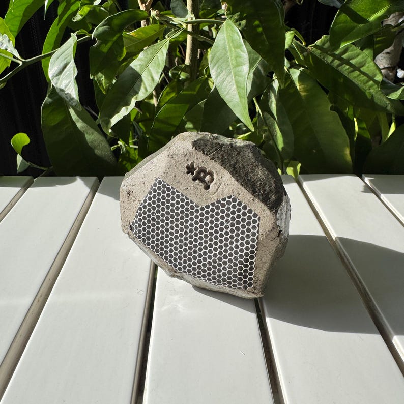 May include: A gray concrete speaker shaped like a rock with a black honeycomb pattern and the text "*B" on the front.