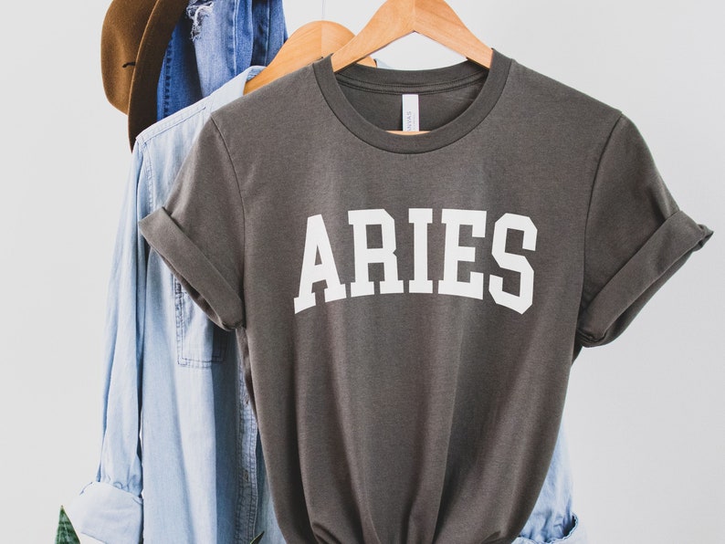 K&ouml;nnte beinhalten: Ein graues T-Shirt mit dem Wort "ARIES" in wei&szlig; auf der Vorderseite.