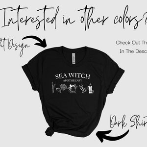 May include: Black t-shirt with a white graphic design that says "Sea Witch Apothecary" with a drawing of a seashell, a mermaid, and a bottle. The text "Interested in other colours? Check Out The Listing In The Description" is written above the shirt.
