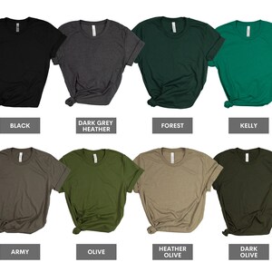 May include: A set of ten blank t-shirts in various colors, including black, dark grey heather, forest, kelly, army, olive, heather olive, and dark olive. The shirts are all folded and laid out on a white background.