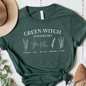 May include: Green t-shirt with the text "Green Witch Apothecary" and illustrations of lavender, sage, bay leaf, rosemary, and thyme.