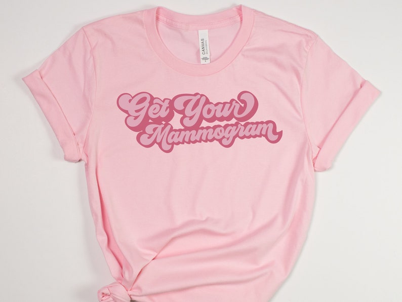 May include: Pink t-shirt with the text "Get Your Mammogram" in a retro pink font.
