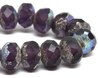 May include: Close-up of a strand of faceted beads. The beads are a deep purple color with a metallic, iridescent finish. The facets catch the light, creating a sparkling effect. These beads are suitable for jewelry making.