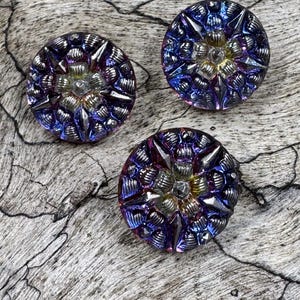 May include: Three iridescent glass buttons with a starburst design in shades of purple, blue, and gold.