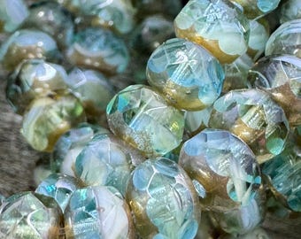 May include: A strand of iridescent glass beads with a light blue and gold color scheme. The beads have a faceted design and are strung on a clear thread.