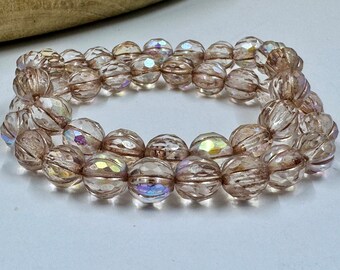May include: A strand of iridescent clear glass beads with a faceted, ribbed design. The beads are a light brown color and have a subtle shimmer.