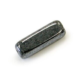 May include: A dark gray, rectangular, glass bead with a smooth, polished surface.
