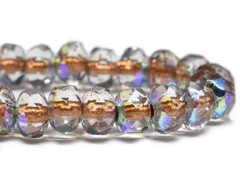 May include: Close-up of a strand of clear, faceted beads with iridescent and copper-colored accents. The beads are oval-shaped and strung together, reflecting light and creating a shimmering effect. The beads are approximately 0.5 inches in diameter.