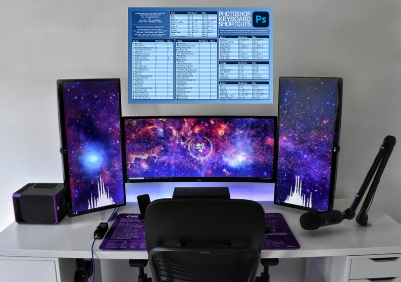 Op de afbeelding: Een wit bureau met een zwarte bureaustoel, drie monitoren die een galactisch thema-achtergrond weergeven, een zwarte microfoonarm en een zwarte computertoren met paarse accenten. Een poster met de tekst "Photoshop-toetsenbordshortcuts" hangt aan de muur.