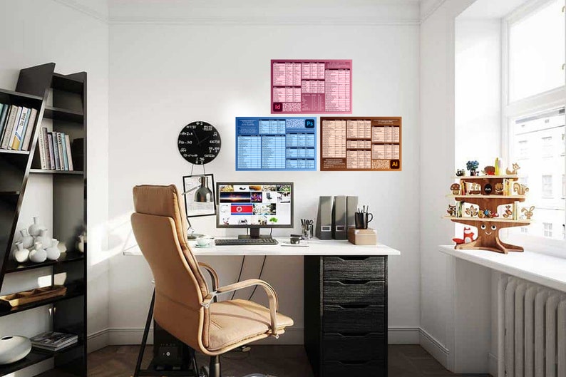 May include: A home office workspace featuring a black desk, a brown leather office chair, a computer monitor, a black clock, and three posters on the wall. The posters are blue, pink, and brown and display text and graphics related to Adobe Photoshop, Illustrator, and InDesign.