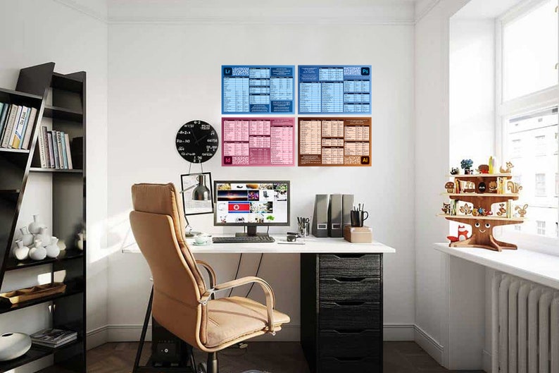 May include: A home office setup with a white desk, computer, and a tan office chair. Four framed charts hang on the wall, with the software names "LR", "Ps", "Id", and "Ai". A black clock and a wooden shelf with decorative items are also visible.
