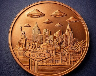 May include: A round copper-toned commemorative coin featuring a relief of the Las Vegas skyline, the Statue of Liberty, and the Welcome to Fabulous Las Vegas sign. Five flying saucer-shaped objects are depicted in the sky above the city buildings.