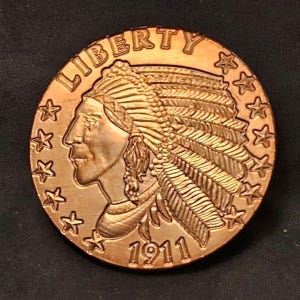 May include: A copper-colored coin featuring a profile of a Native American in a feathered headdress. The word "LIBERTY" is arched across the top, with stars around the edge. The year "1911" is at the bottom.