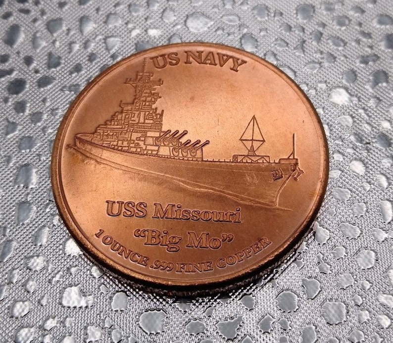 Puede incluir: Una moneda de color cobre con una representaci&oacute;n del acorazado USS Missouri y el texto "US NAVY" y "USS Missouri "Big Mo" 1 OUNCE .999 FINE COPPER".