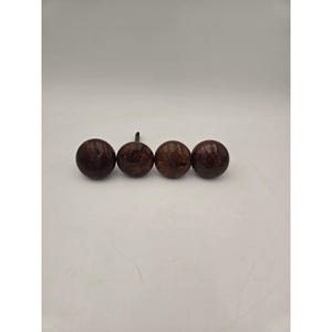 May include: Four spherical cabinet knobs with a dark brown, mottled, stone-like finish. Each knob features a smooth, rounded surface and a small, dark metal mounting screw protruding from the back of one of the pieces, arranged in a horizontal row.