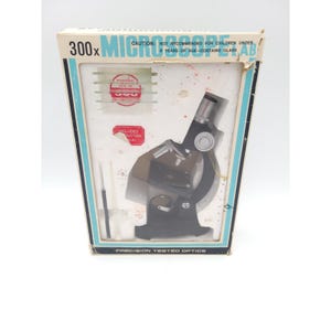 May include: A vintage 300x microscope lab kit in its original box. The box is white with blue and teal accents and features the text "MICROSCOPE LAB" and "PRECISION TESTED OPTICS". The kit includes a microscope, slides, and instructions.