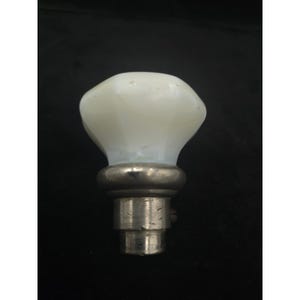 May include: A white, opaque glass cabinet knob with a rounded top and a silver-colored metal base. The knob has a vintage aesthetic and is set against a dark background.