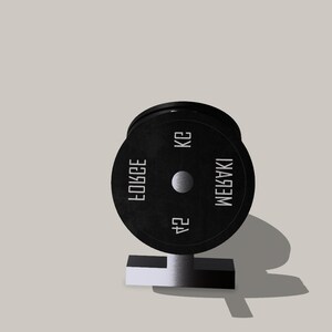 Op de afbeelding: Een zwarte gewichtsplaat met de tekst "MEGABAKI 24 KG FORCE" erop.
