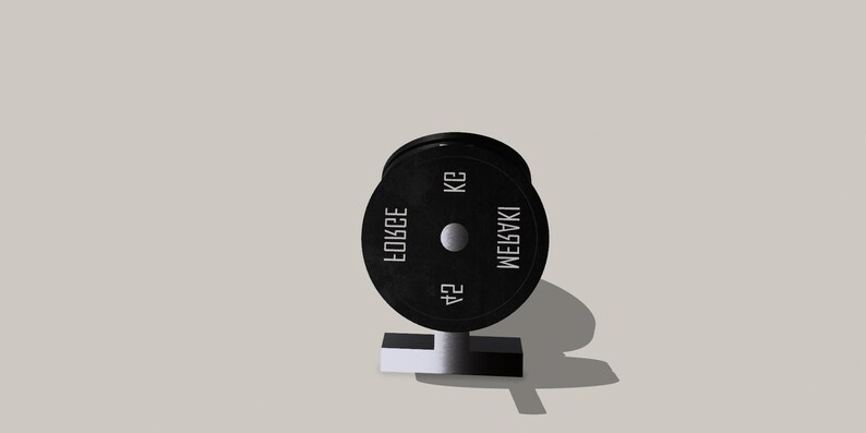 Op de afbeelding: Een zwarte gewichtsplaat met de tekst "MEGABAKI 24 KG FORCE" erop.