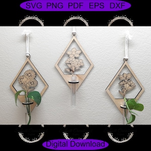 Op de afbeelding: Drie houten, ruitvormige wandhangers met bloemmotieven en een klein glazen buisje om een ​​plantensteekling in te houden. Elke hanger heeft een wit koord om op te hangen.