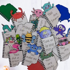 May include: A collection of small, colorful, wooden notebooks with different animal illustrations and positive messages. The messages include "You are special", "You are smart", "You make me laugh", "You are my sunshine", and "Thank you for being great".