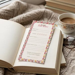Puede incluir: Un libro abierto con un marcapáginas "Flash Book Review" con bordes florales. El marcapáginas incluye secciones para el título del libro, el autor, la calificación y una recomendación. Una taza de café y una pila de libros están en el fondo.