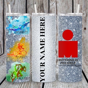 Pu&ograve; includere: Tre bicchieri argentati glitterati con coperchi e cannucce. Il primo presenta grafiche acquerellate blu, gialle e verdi di un nuotatore, un ciclista e un corridore con il testo 2.4 MILES, 112 MILES e 26.2 MILES. Il secondo riporta YOUR NAME HERE. Il terzo ha un logo rosso e il testo ANYTHING IS POSSIBLE.