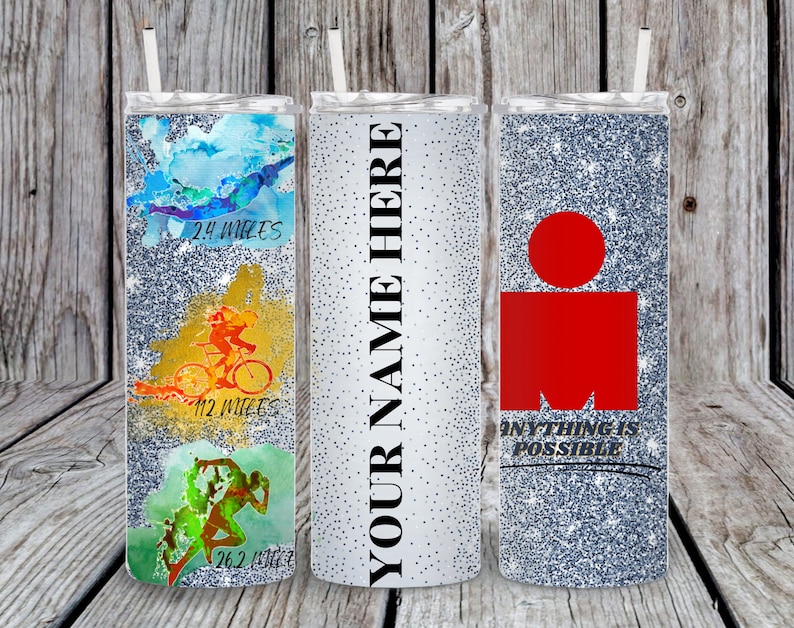 Pu&ograve; includere: Tre bicchieri argentati glitterati con coperchi e cannucce. Il primo presenta grafiche acquerellate blu, gialle e verdi di un nuotatore, un ciclista e un corridore con il testo 2.4 MILES, 112 MILES e 26.2 MILES. Il secondo riporta YOUR NAME HERE. Il terzo ha un logo rosso e il testo ANYTHING IS POSSIBLE.