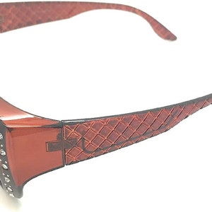 May include: Brown plastic sunglasses with a diamond-shaped pattern on the arms and rhinestones around the lenses.