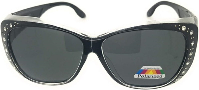 May include: Black cat-eye sunglasses with rhinestones on the frame and polarized lenses. The sunglasses have a silver accent on the top of the frame and a label that reads "Sunglasses Polarized".
