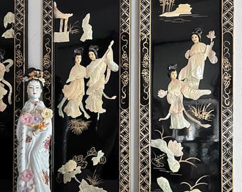 May include: A porcelain figurine of a woman holding flowers stands before three black lacquered panels. The panels feature mother-of-pearl inlay depicting Asian landscapes and figures, framed in gold.