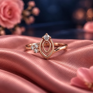 May include: A rose gold ring featuring a marquise-shaped centerpiece with a single round brilliant-cut diamond at the top. The band includes a cluster of three small round diamonds on one side, set in a polished metal finish with a smooth shank.