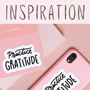 Puede incluir: Dos superficies rosas con pegatinas blancas que dicen "Practica la gratitud" en escritura negra. Las pegatinas est&aacute;n en una agenda rosa y una funda de tel&eacute;fono rosa. El texto "COMPRAR AHORA" est&aacute; en un bot&oacute;n blanco con un icono de bolsa de la compra.