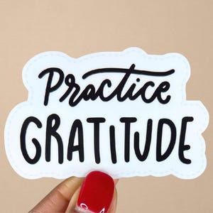 Puede incluir: Pegatina blanca con texto negro que dice "Practica la gratitud".
