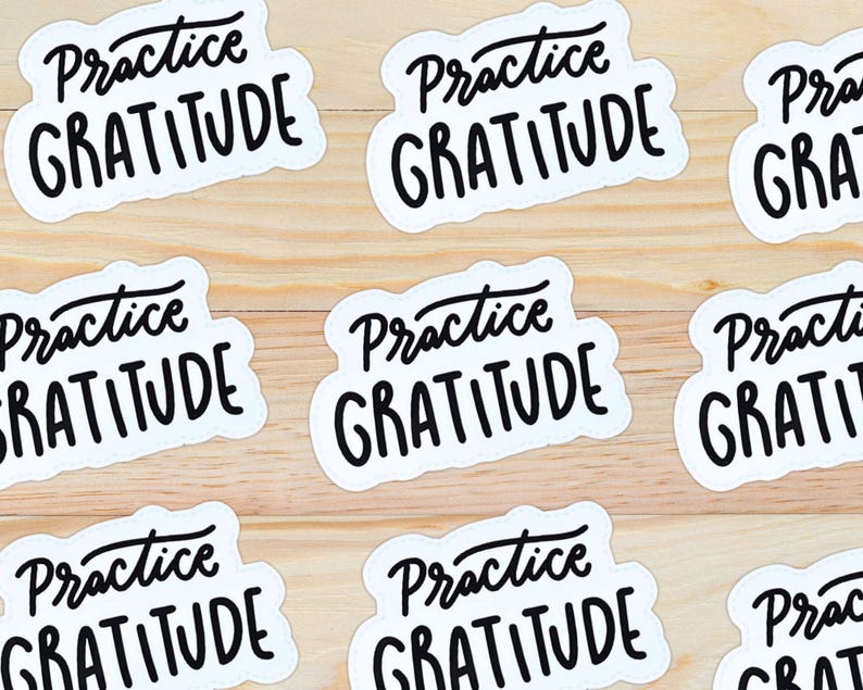 Puede incluir: Nueve pegatinas blancas con texto negro que dice "Practica la gratitud" sobre un fondo de madera claro.
