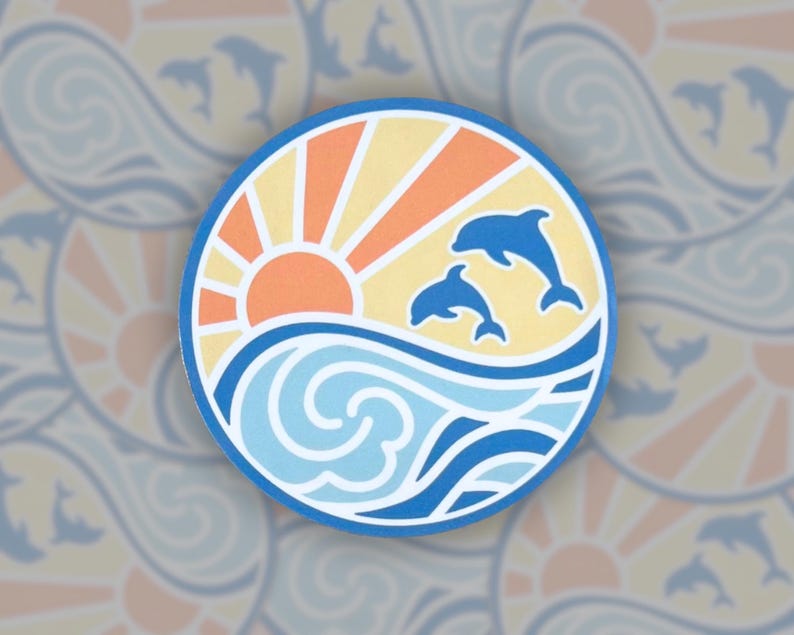 Puede incluir: Una pegatina redonda con una puesta de sol, olas del oc&eacute;ano y dos delfines saltando fuera del agua. La puesta de sol es naranja y amarilla, las olas son azules y blancas, y los delfines son azules.