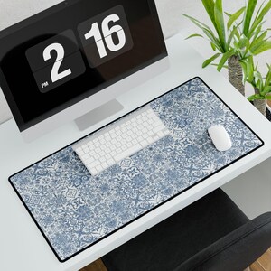 May include: A rectangular desk mat with a blue and white tile pattern, a black border, and a white keyboard and mouse. A computer monitor displays the time as 2:16 PM.