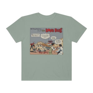 Puede incluir: Una camiseta azul claro con una ilustración de cómic vintage de un Volkswagen Beetle. El panel del cómic presenta el texto "Walt Disney Productions Presents The Love Bug" y "S-y-y-y-SPTT!"