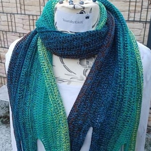May include: A teal, green, and blue ombre crochet scarf with a brown stripe. The scarf is displayed on a white mannequin with the text "YoursbyKiki" on the label.